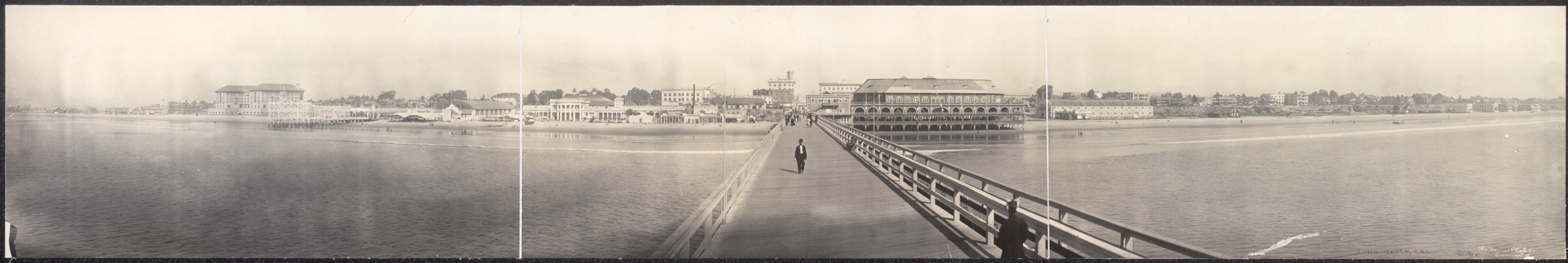 Panoramic photograph of a long pier and waterfront buildings — historic photograph