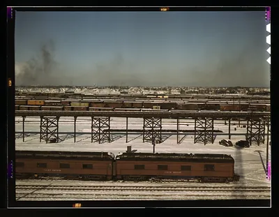 Snowy rail yard with passenger cars and steel trestles