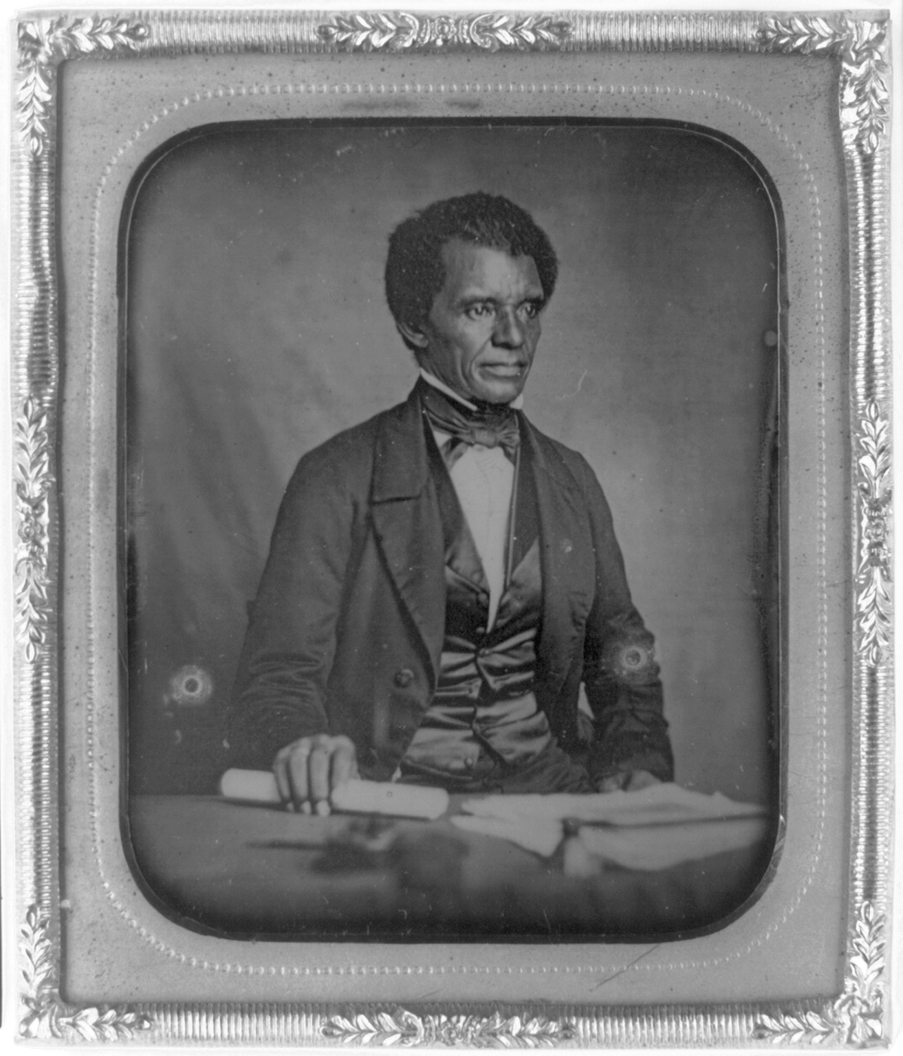 [Beverly Page Yates, half-length portrait, facing slightly right, seated at table, holding rolled piece of paper], [between 1856 and 1860] — historic photograph