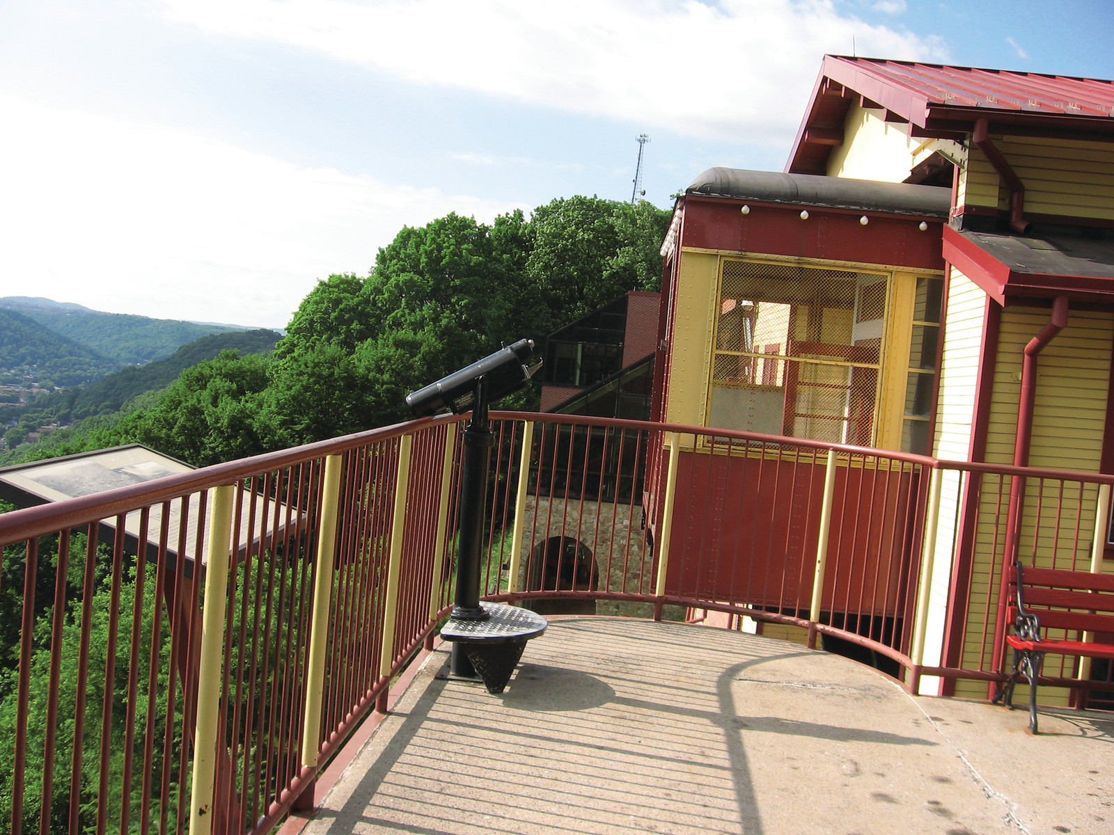 Hilltop viewing platform with coin telescope beside yellow station building — historic image