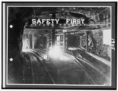 Mine tunnel with rail tracks under a "SAFETY FIRST" sign