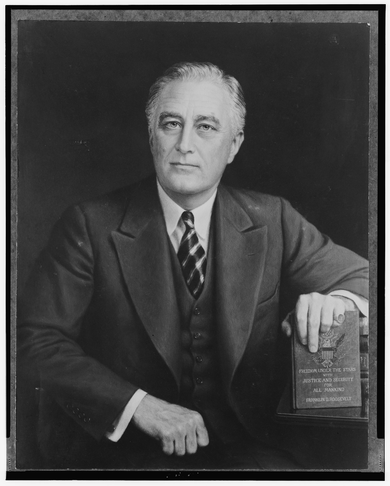 [Franklin Roosevelt, half-length portrait, seated, facing slightly left, with hand resting on his book titled Freedom under the stars with justice and security for all mankind"]", c1943. — historic photograph