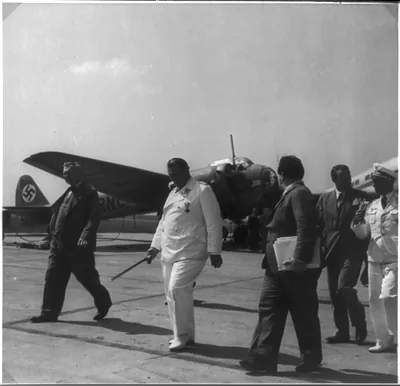 [Goering inspecting Junkers aircraft plant in Dessau, Germany - walking with 4 officials; JU bomber in background]