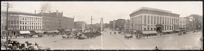 Panoramic street view of a town square with horse-drawn carriages