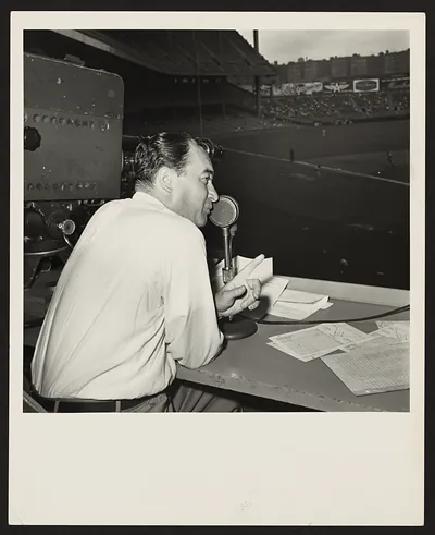 Broadcaster at microphone in a baseball stadium booth