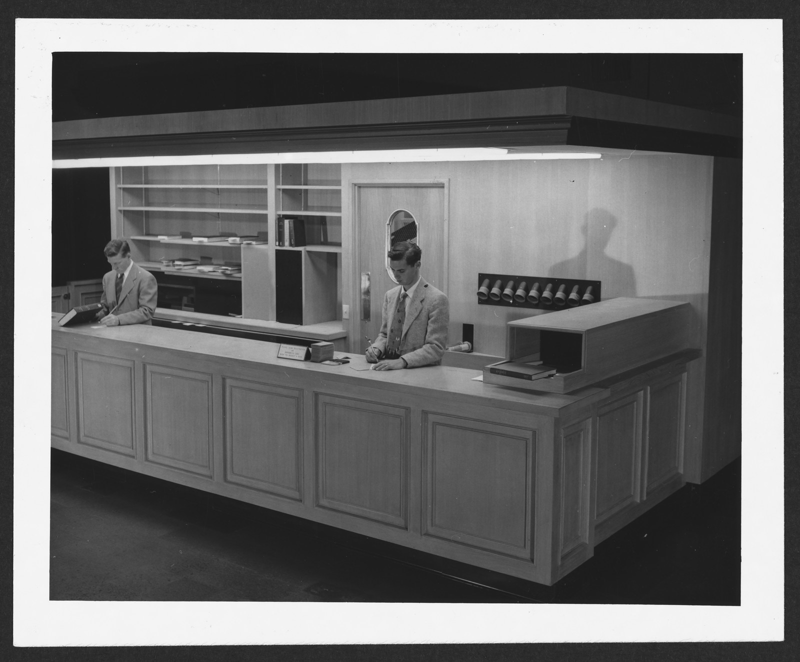 Library circulation desk with two attendants, black and white photograph — historic photograph