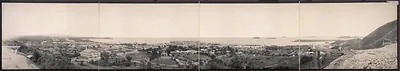 Panoramic view of a coastal town from a hill, with bay and islands