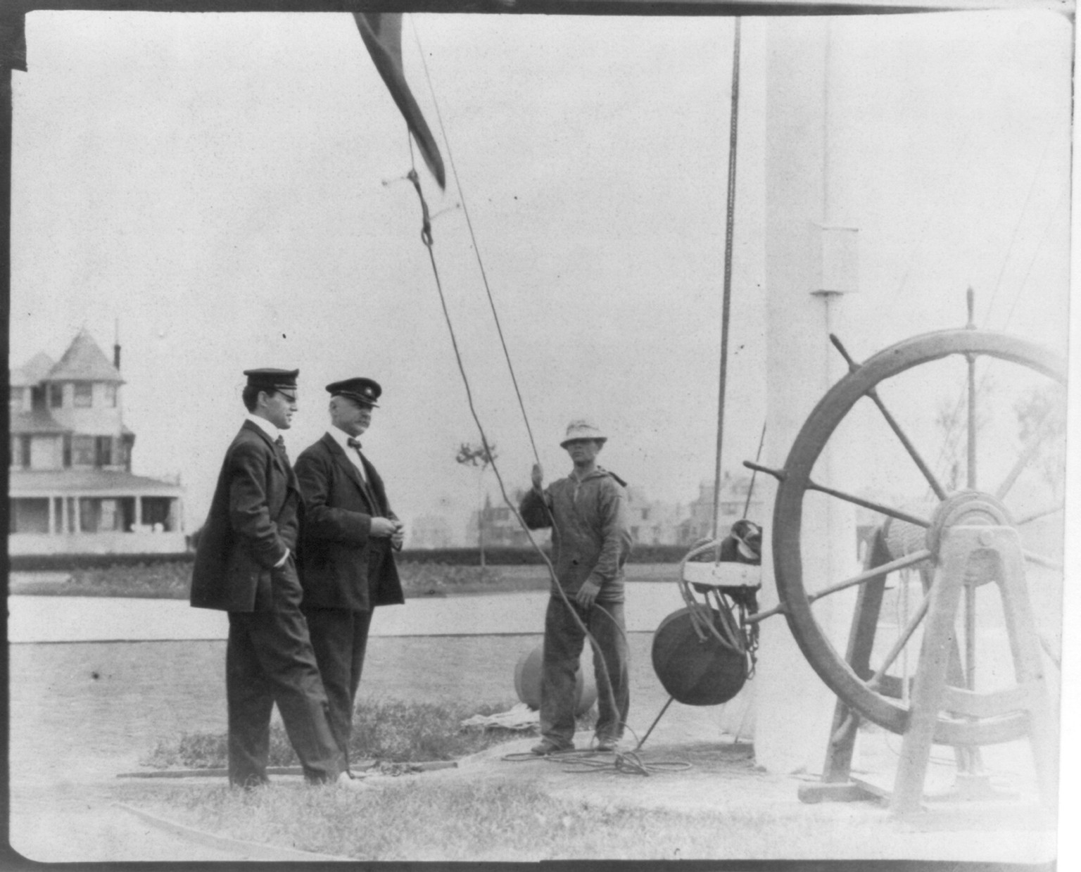 [New York Yacht Club, Oyster Bay, L.I., 1905: 2 men watching sailor hoist flag], 1905 — historic photograph
