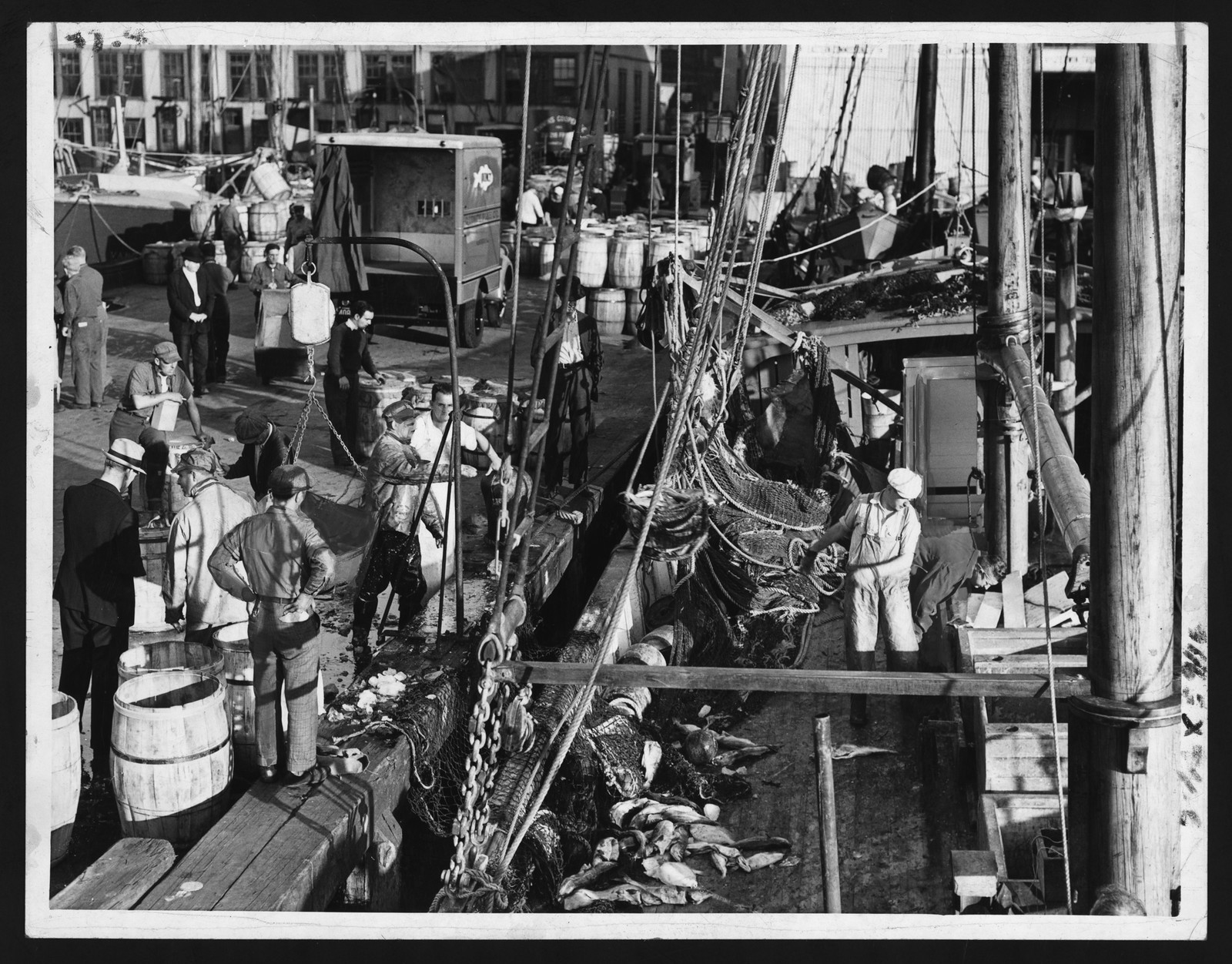 Fishing boats unloading the day's catch at a dock — historic image