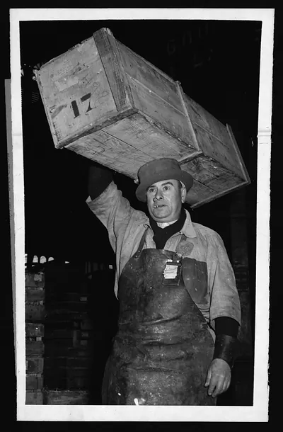 Market porter carrying a numbered wooden crate on his head