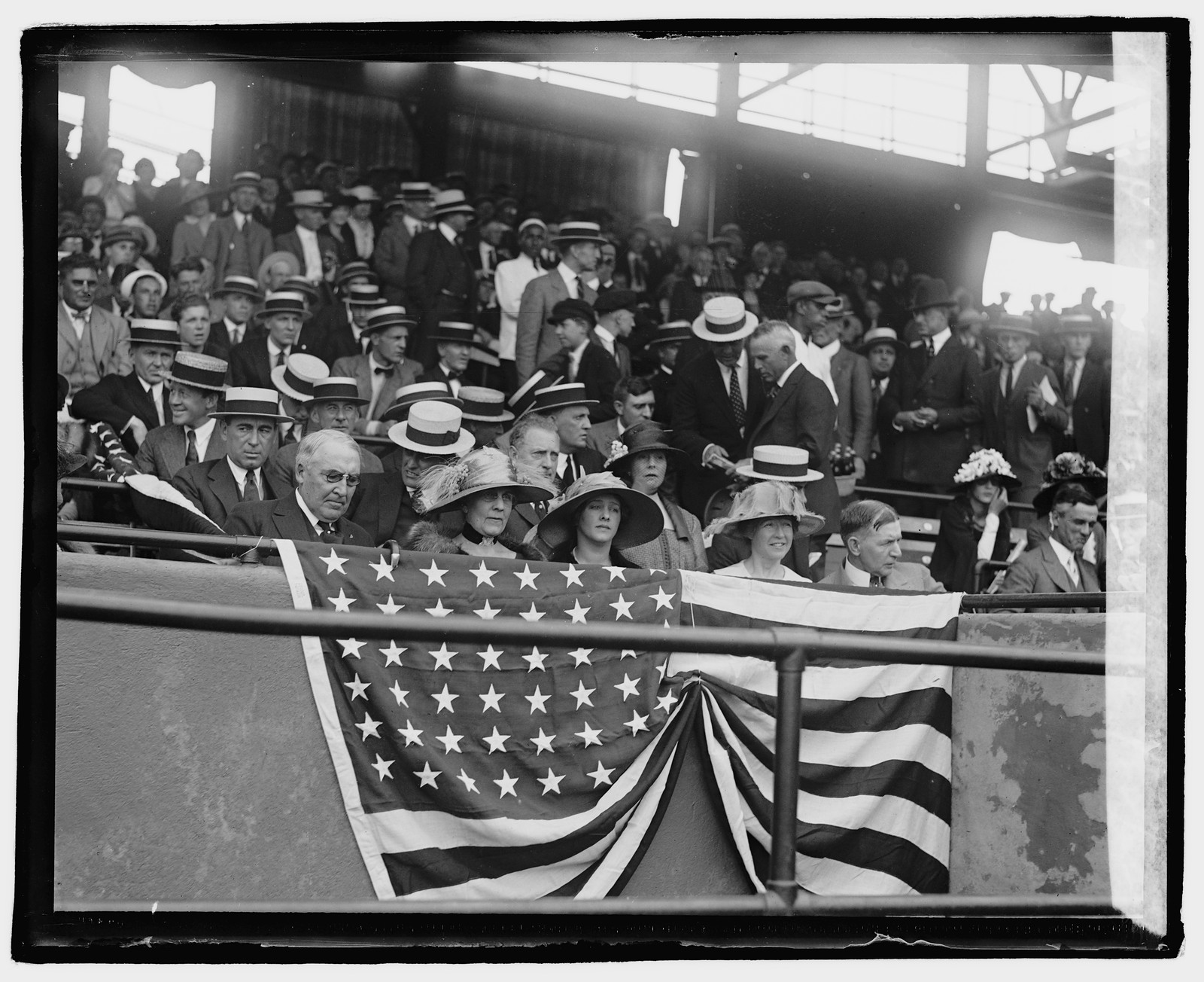 Spectators in grandstand with flag bunting, straw boaters — historic image