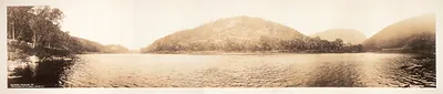 Sepia panoramic photograph of river and wooded hills