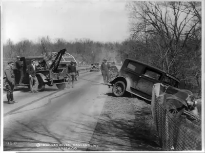 [Wrecker hauling an auto up a bank]