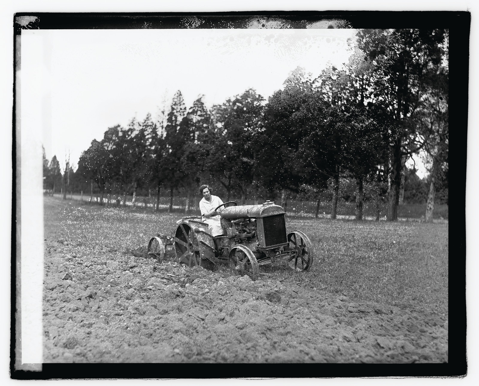Woman driving tractor plowing a field, early photograph — historic photograph