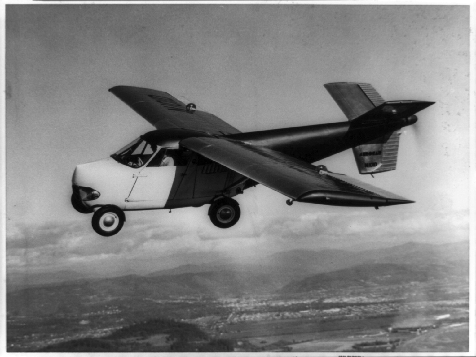 Aerocar flying automobile in flight over hills — historic image