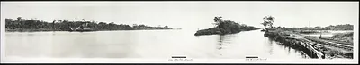 Panoramic black-and-white view of a canal waterway with railway tracks