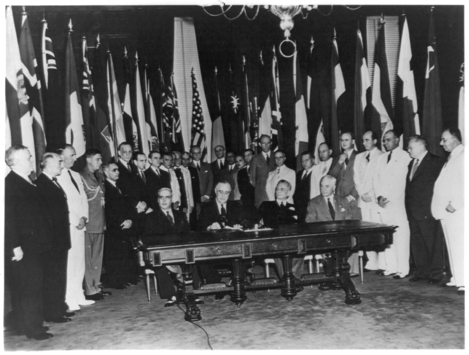 Franklin Roosevelt signing a document, surrounded by international dignitaries, [between 1940 and 1944] — historic photograph