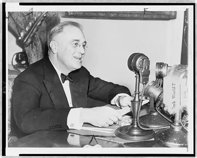 [President Franklin D. Roosevelt, head-and-shoulders portrait, facing right, seated behind microphone, during Fireside chat"]"