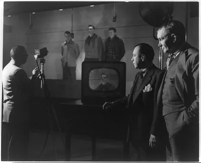 TV broadcast over a closed circuit emanating from the Police Department Headquarters on Centre Street to Brooklyn Police Headquarters on Bergen Street where the mock lineup was viewed by police officials. Mayor Wagner and Police Commissioner Francis Adams watch while the mock lineup is televised
