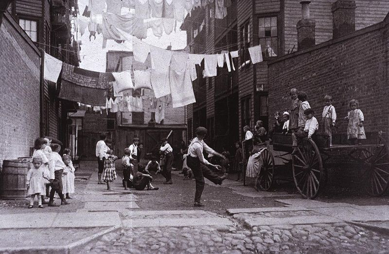 Children playing in a tenement alley under laundry lines — historic image