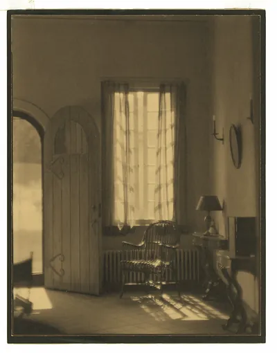 Sunlit interior with arched door and wicker chair