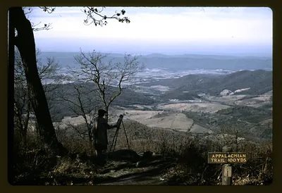 Person with tripod at overlook above valley, Appalachian Trail sign