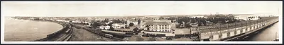 Panoramic view of a waterfront town with pier and railway tracks