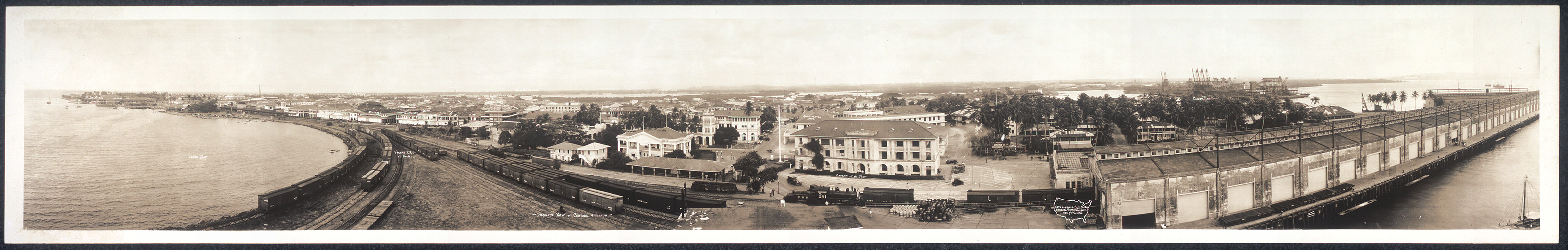 Panoramic view of a waterfront town with pier and railway tracks — historic image