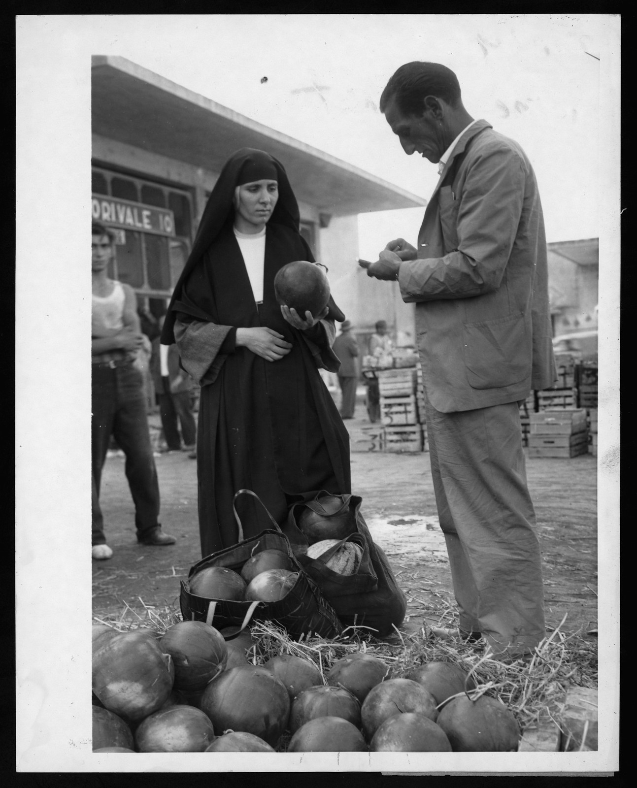 Nun and man inspecting melons at a market — historic image