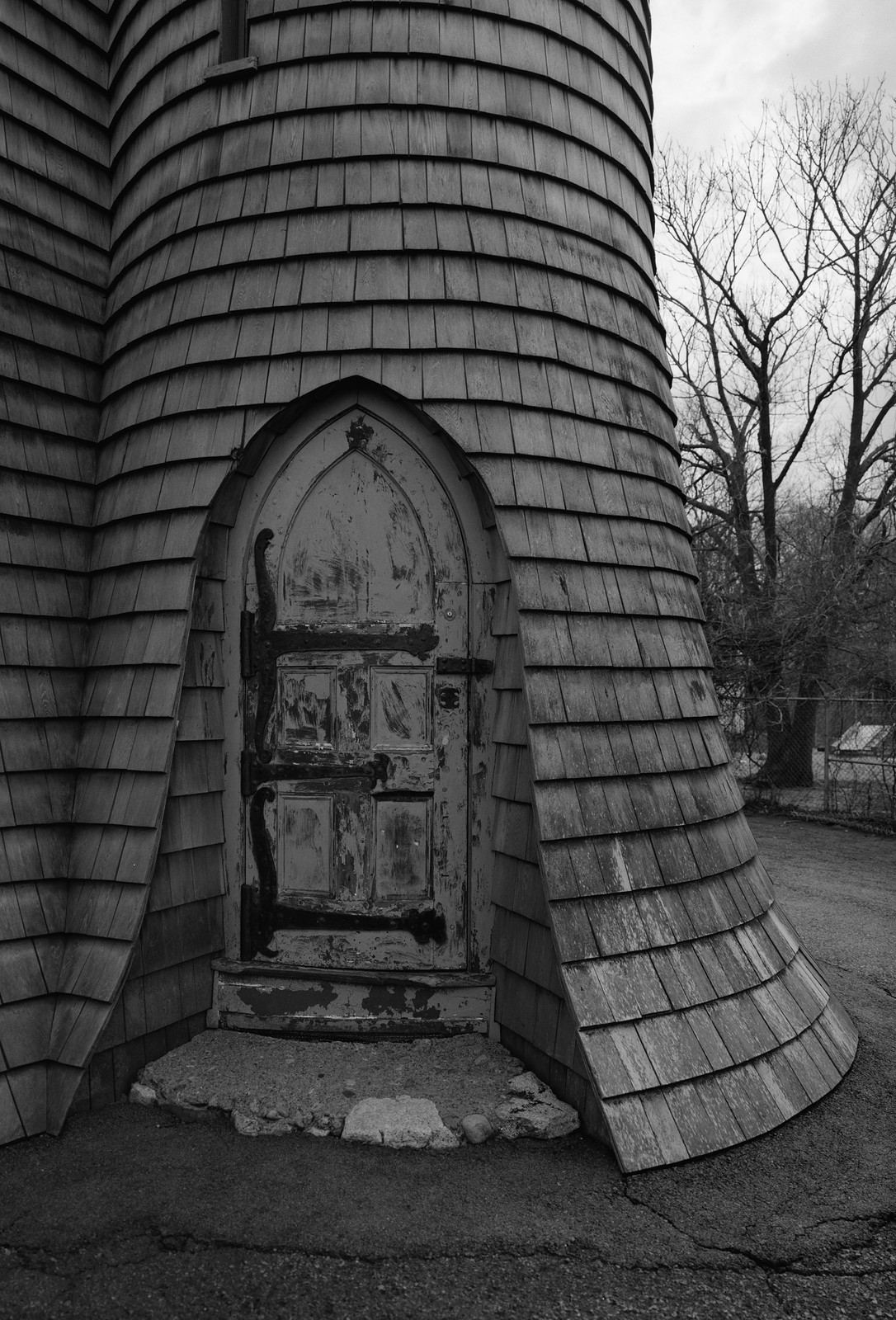 Shingled curved tower with arched wooden door, black and white photograph — historic photograph