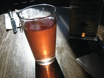 Pint glass of amber beer on a wooden table