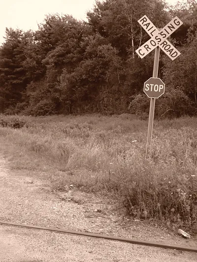 Railroad crossing sign and stop sign beside tracks