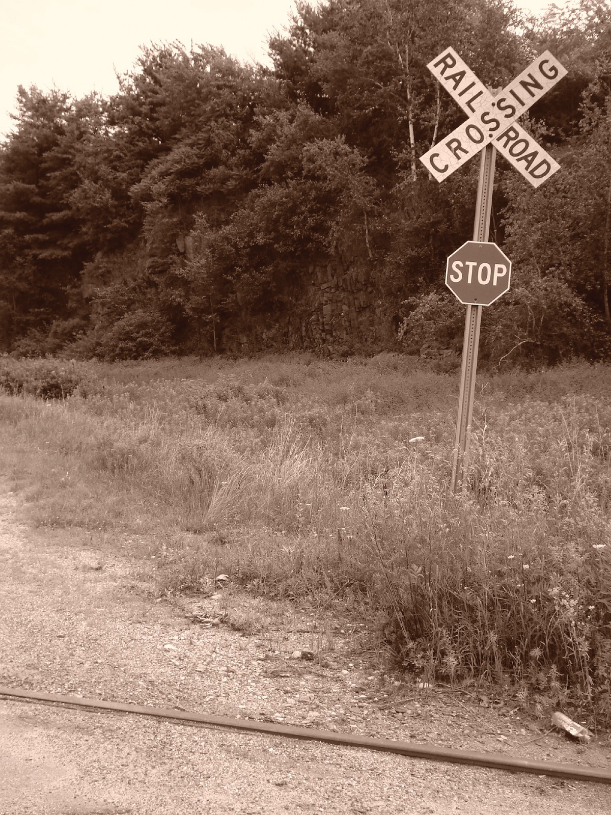 Railroad crossing sign and stop sign beside tracks — historic image