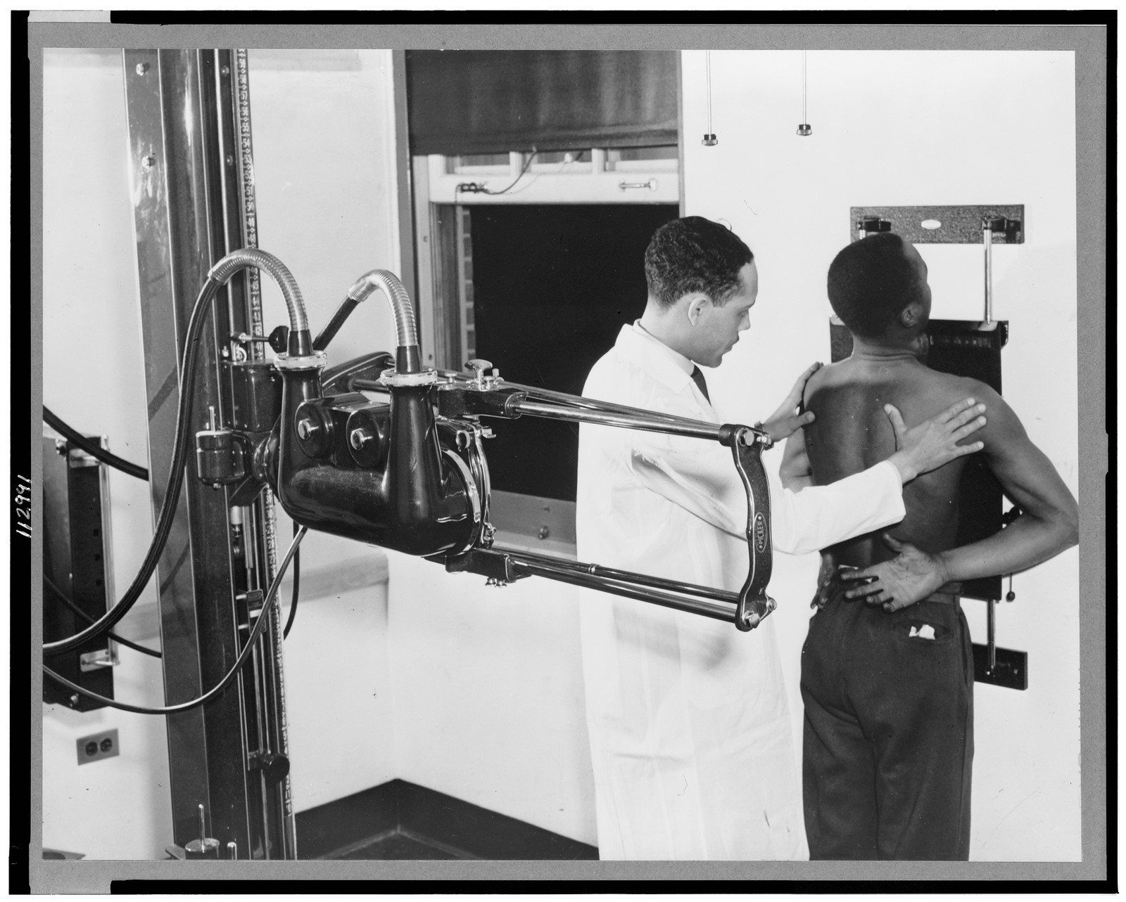 Doctor placing patient in the correct position for taking chest x-ray for use in the diagnosis, 1937 — historic photograph