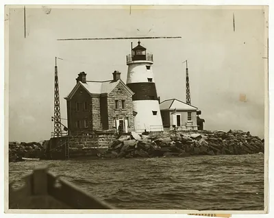 Black and white lighthouse with stone keeper's house on rocks