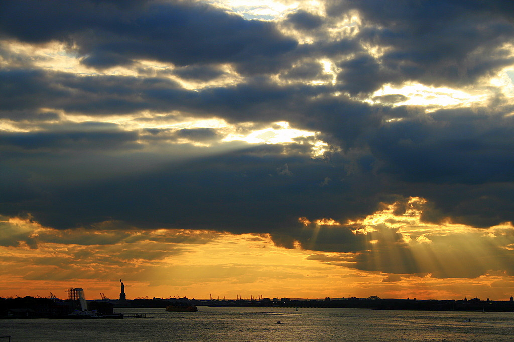 Sunset rays over New York harbor with Statue of Liberty — historic image
