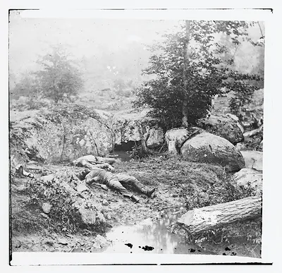 Dead soldiers lying among boulders beside a stream