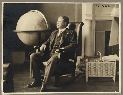 Seated man in leather chair beside a globe