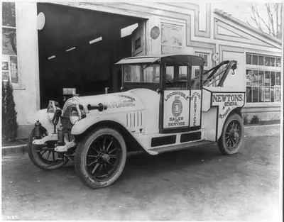 [Locomobile tow truck parked in front of garage]