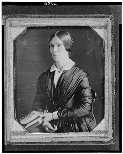 [Unidentified woman, half-length portrait, facing left, seated holding book]