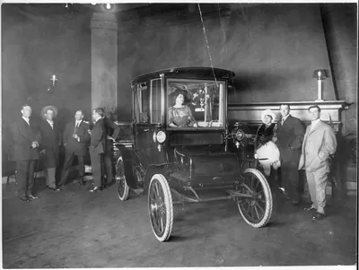 [Mary Garden, posed in electric auto, in showroom]