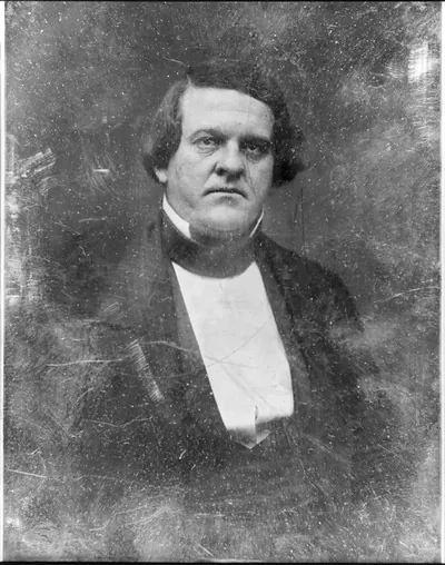 Halflength portrait of a man in dark coat and white bib