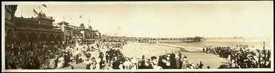 Crowded beach with arcaded pavilion and long pier, sepia panorama