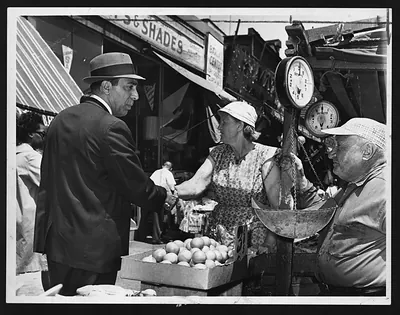 Man in fedora shaking hands with vendor at produce stand