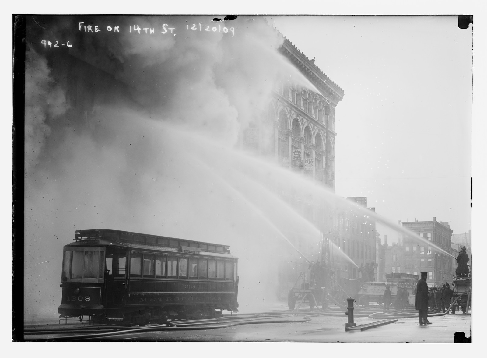 Firemen spraying burning building on 14th St., trolley in foreground, New York, 12/20/09. — historic photograph