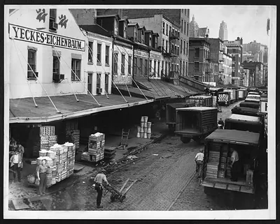 Trucks being loaded with produce on a city street