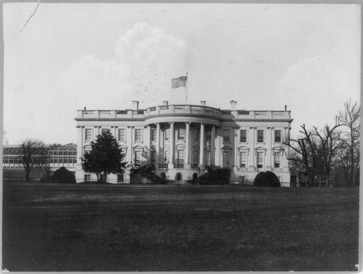 [The White House, Washington, D.C., south facade, with large conservatory wing at left and American flag flying above], [between 1898 and 1914] — historic print