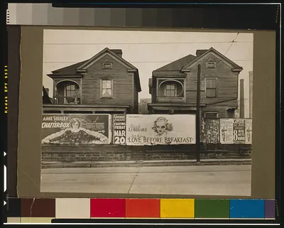 Two wooden houses behind theater posters for Love Before Breakfast