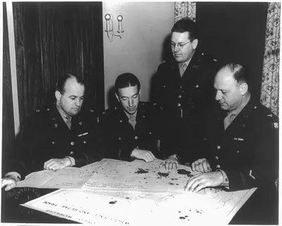 [Col. Karl R. Bendetsen, Major Hugh T. Fullerton, Major Albert H. Hoffitt, Jr., and Col. William A. Boekel looking at Japanese evacuation maps]