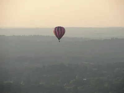 Hot air balloon over hazy countryside at dusk